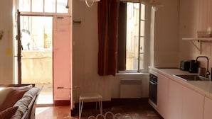 A compact kitchen with a dining area, a window with curtains, and a view of the outside. - charming fisherman house (Gruissan)