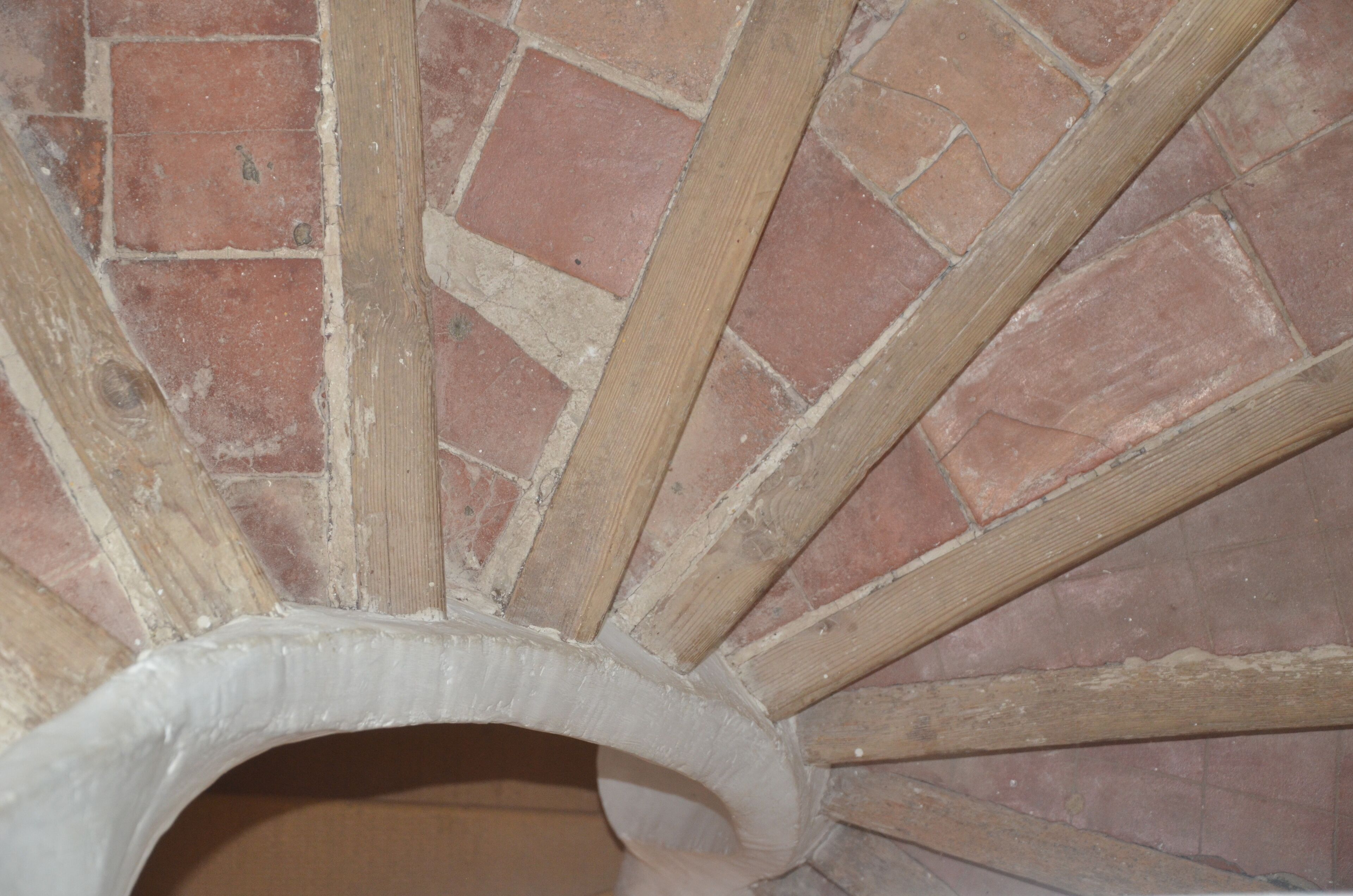A close-up of a brick wall with wooden beams and a curved white structure.
