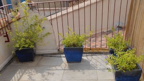 A tiled patio with potted plants and a metal railing. - charming fisherman house (Gruissan)