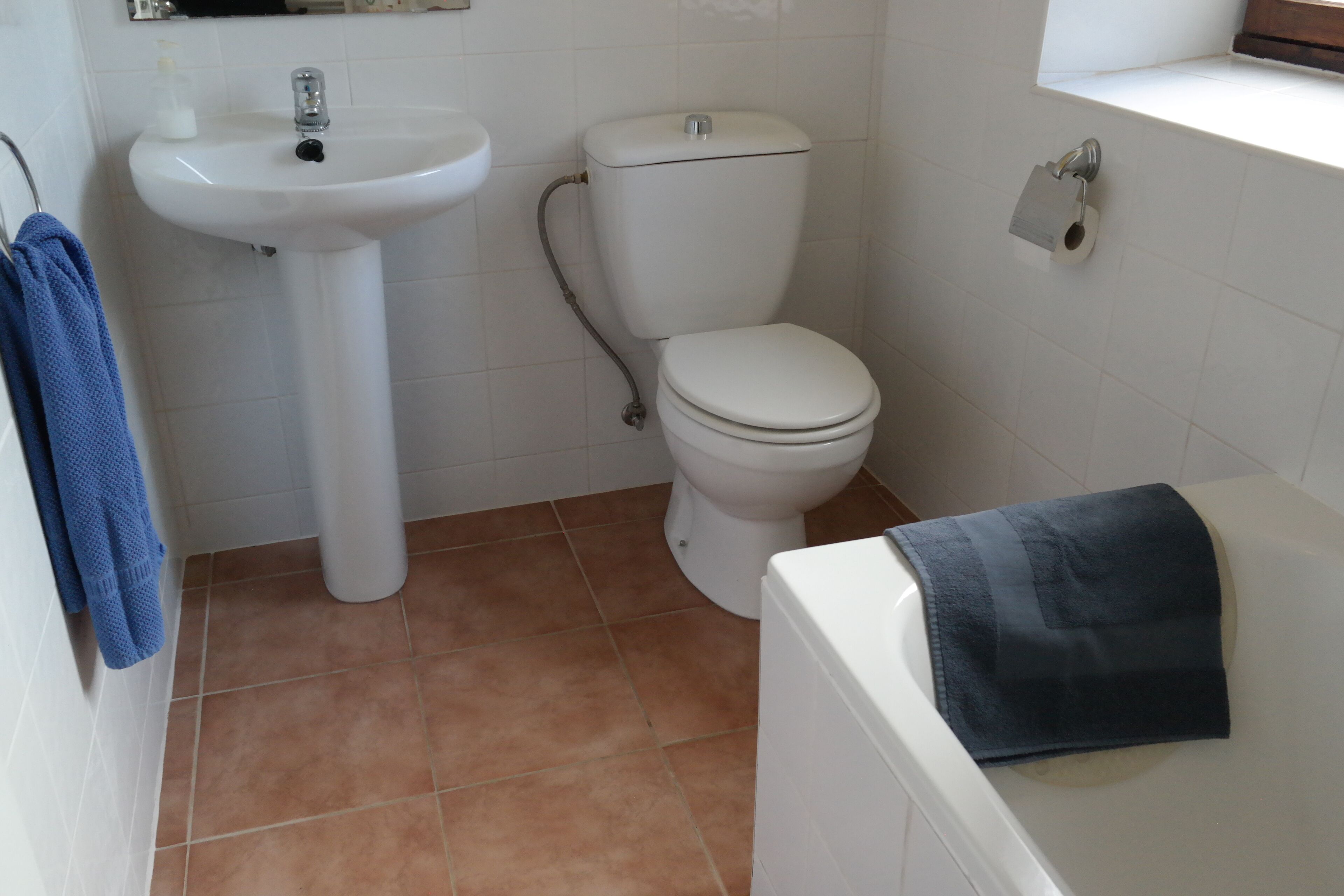 Une salle de bain avec un lavabo, des toilettes et une baignoire, le tout de couleur blanche.