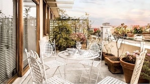 A rooftop terrace with a round table and four chairs, surrounded by potted plants and a view of the cityscape. - The best choice for your vacation in Venice! (Venezia)