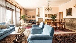 A spacious living room with a blue sofa, a coffee table, and a dining area with a chandelier. - The best choice for your vacation in Venice! (Venezia)