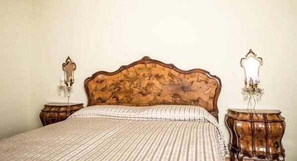 A bedroom with a wooden headboard, a patterned bedspread, and two nightstands with lamps. - The best choice for your vacation in Venice! (Venezia)
