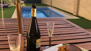 Een houten tafel met een champagnefles, twee glazen en een bord met een plak cake en partjes citroen.