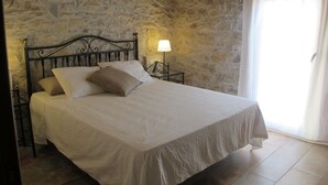 Een bed in een kamer met stenen muren en een houten plafond.