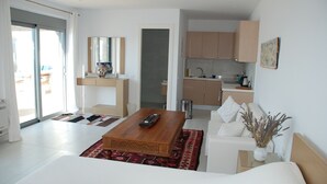 A modern living room with a wooden coffee table, a sofa, and a kitchen area in the background.