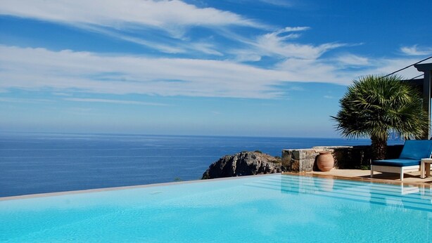 A clear blue sky, a swimming pool, and a view of the ocean.