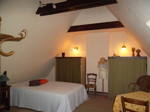 Cozy loft-style accommodation with a single bed, table, and chair, offering a warm and inviting atmosphere.