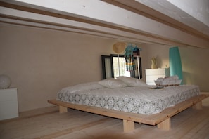 Relax in this serene bedroom featuring a low platform bed, a lace bedspread, and a comfortable bench at the foot.