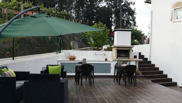 An outdoor patio with a dining area, a grill, and a staircase leading to an upper level.