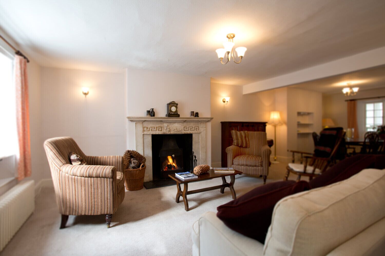 A cozy living room with a fireplace, striped armchairs, a sofa, and a coffee table.