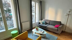 A living room with a sofa, a yellow armchair, a coffee table, and a floor lamp. - Charm and garden view, in the center of Paris, near Montparnasse (Paris)