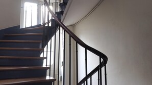 A spiral staircase with wooden steps and black metal railings, leading to an upper floor. - Charm and garden view, in the center of Paris, near Montparnasse (Paris)