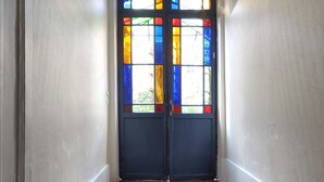 A hallway with a double door featuring stained glass windows, a patterned floor, and white walls. - Charm and garden view, in the center of Paris, near Montparnasse (Paris)