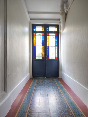 A hallway with a double door featuring stained glass windows, a patterned floor, and white walls. - Charm and garden view, in the center of Paris, near Montparnasse (Paris)