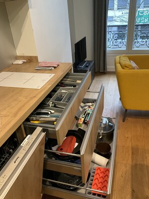 Eine Küche mit Holzarbeitsplatten, einem gelben Stuhl und Blick auf die Straße durch ein Fenster.