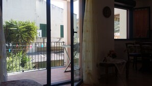 A room with a balcony, a small table with a vase, and a chair. - Apartment 2 km from the sea, 200 meters from the historic center of bosa (Bosa, Oristano)