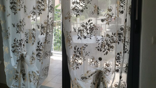 A room with a sliding glass door covered by floral sheer curtains. - Apartment 2 km from the sea, 200 meters from the historic center of bosa (Bosa, Oristano)