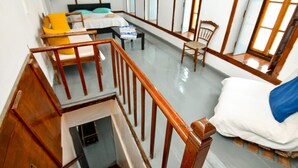 Une pièce avec un lit, une chaise, une petite table et une fenêtre.