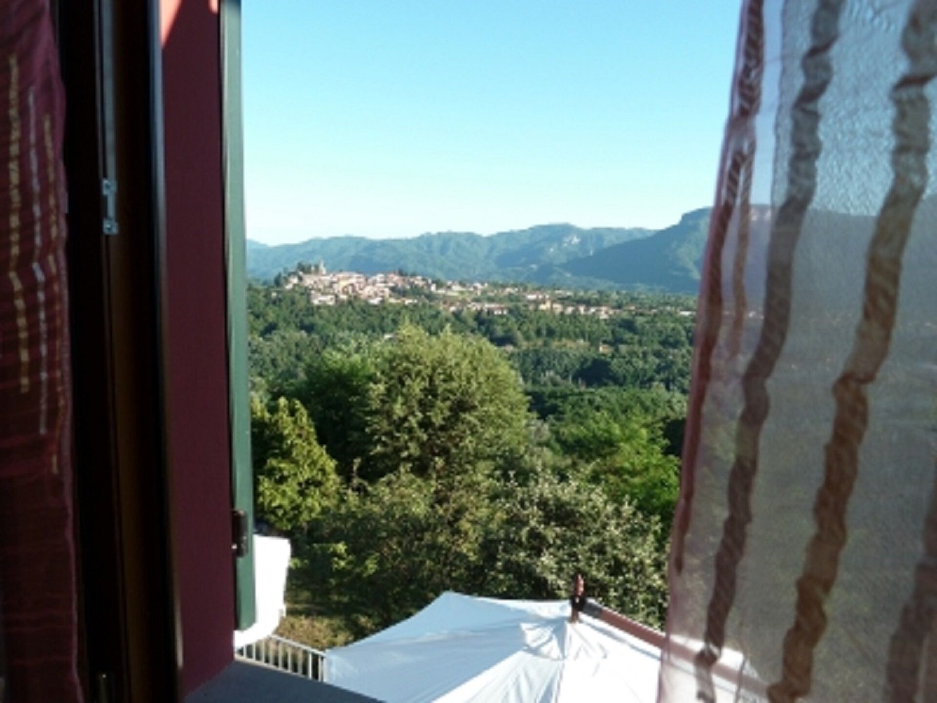 Une chambre avec vue sur un paysage montagneux et un village situé en contrebas.
