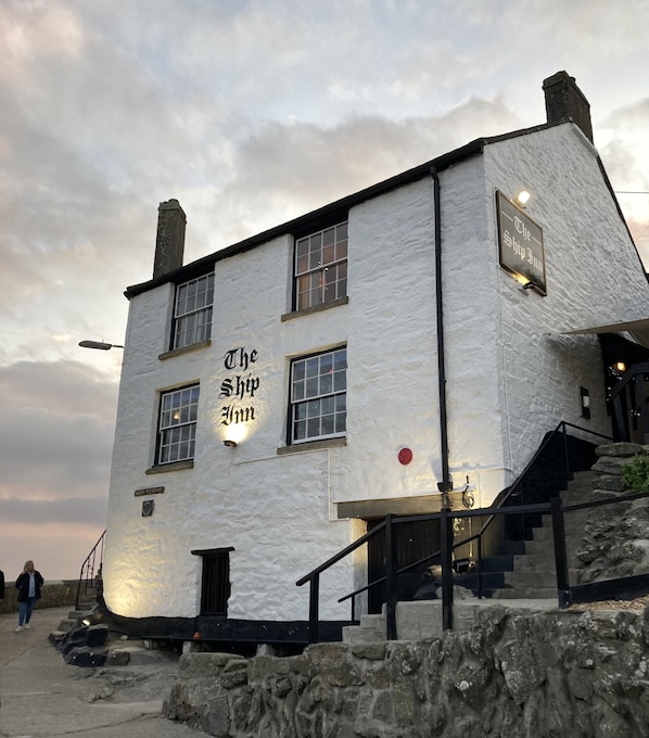 A white building with a sign reading "The Ship Inn" and a staircase leading to the entrance. - Holiday House 400M walk to beach & 100M to harbour with private Sunny Garden. (Porthleven)