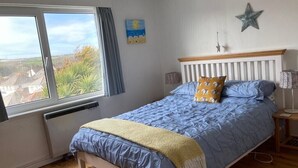 A bedroom with a bed, a window, a star decoration, and a painting on the wall.