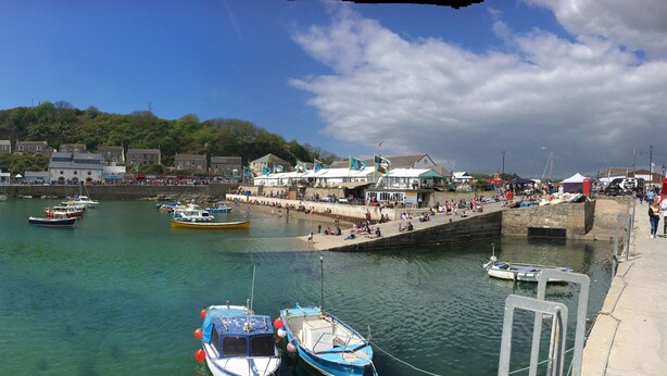 A harbor with boats docked, a stone wall, and buildings in the background.