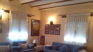 Un salon chaleureux avec deux canapés bleus à motifs, une table basse et un lit recouvert d’une couvre-lit à fleurs.