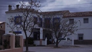 A two-story building with a tiled roof, a balcony, and a gated entrance.