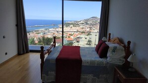 Camera da letto con un'ampia finestra vista sulla città costiera.