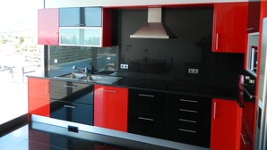 Una cucina moderna con mobili neri e rossi, elettrodomestici in acciaio inossidabile e un'ampia finestra che offre vista sull'esterno.