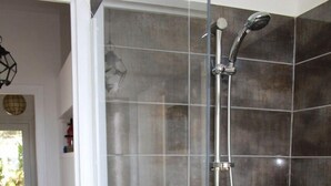 A glass-enclosed shower with a handheld showerhead and a wall-mounted faucet. - Residential flat (Ensuès-La-Redonne)