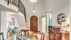 Un comedor con una mesa de madera, sillas, un florero con plantas y un plato decorativo.