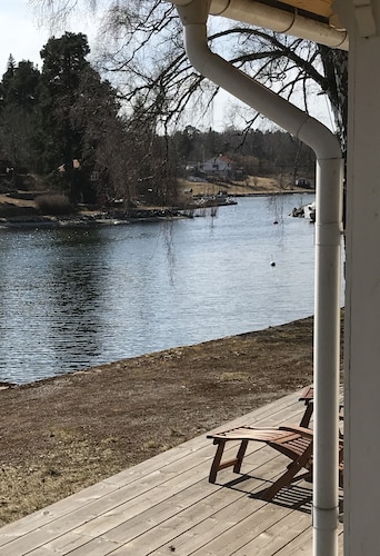 Cottage mit sonnigem Holzdeck am Wasser. 