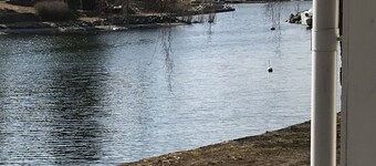 Cottage with sunny wooden deck by water. Rowing boat included.