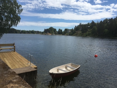 Cottage with sunny wooden deck by water. Rowing boat included.