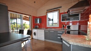 A kitchen with a washing machine, microwave, and a large window.