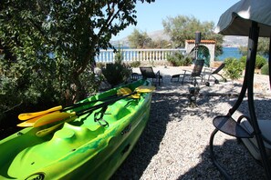 Relax by the water's edge, where a kayak and paddles await, and a scenic view unfolds.