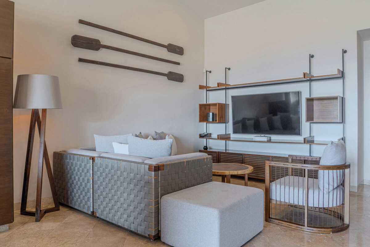 A modern hotel room with a bed, seating area, and a TV.