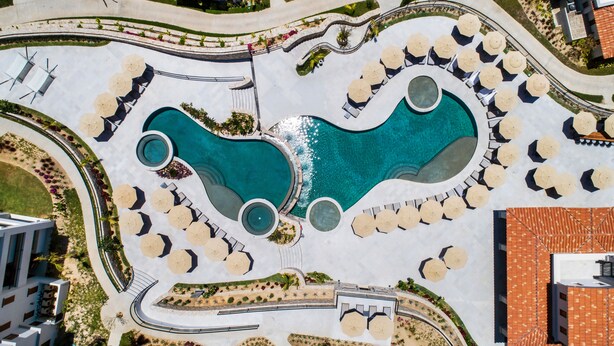 An aerial view of a resort with multiple swimming pools, sun loungers, and umbrellas. - Live Aqua Private Residences Los Cabos (Cabo San Lucas)