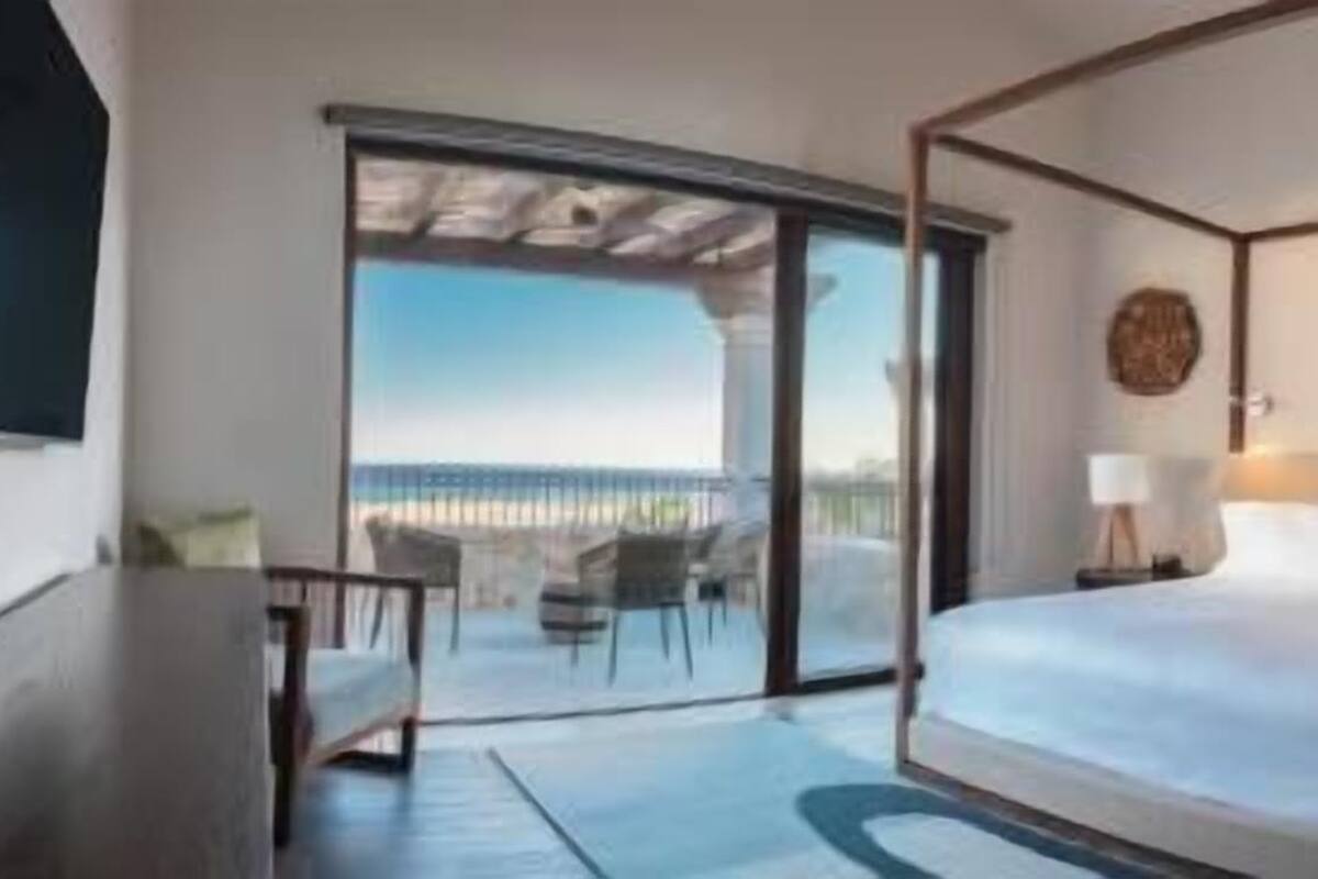 Une chambre d’hôtel avec un lit à baldaquin, un bureau, une chaise et un balcon avec vue.