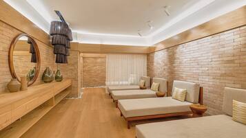 A modern hotel room with a wooden floor, brick walls, and three beds with headboards.