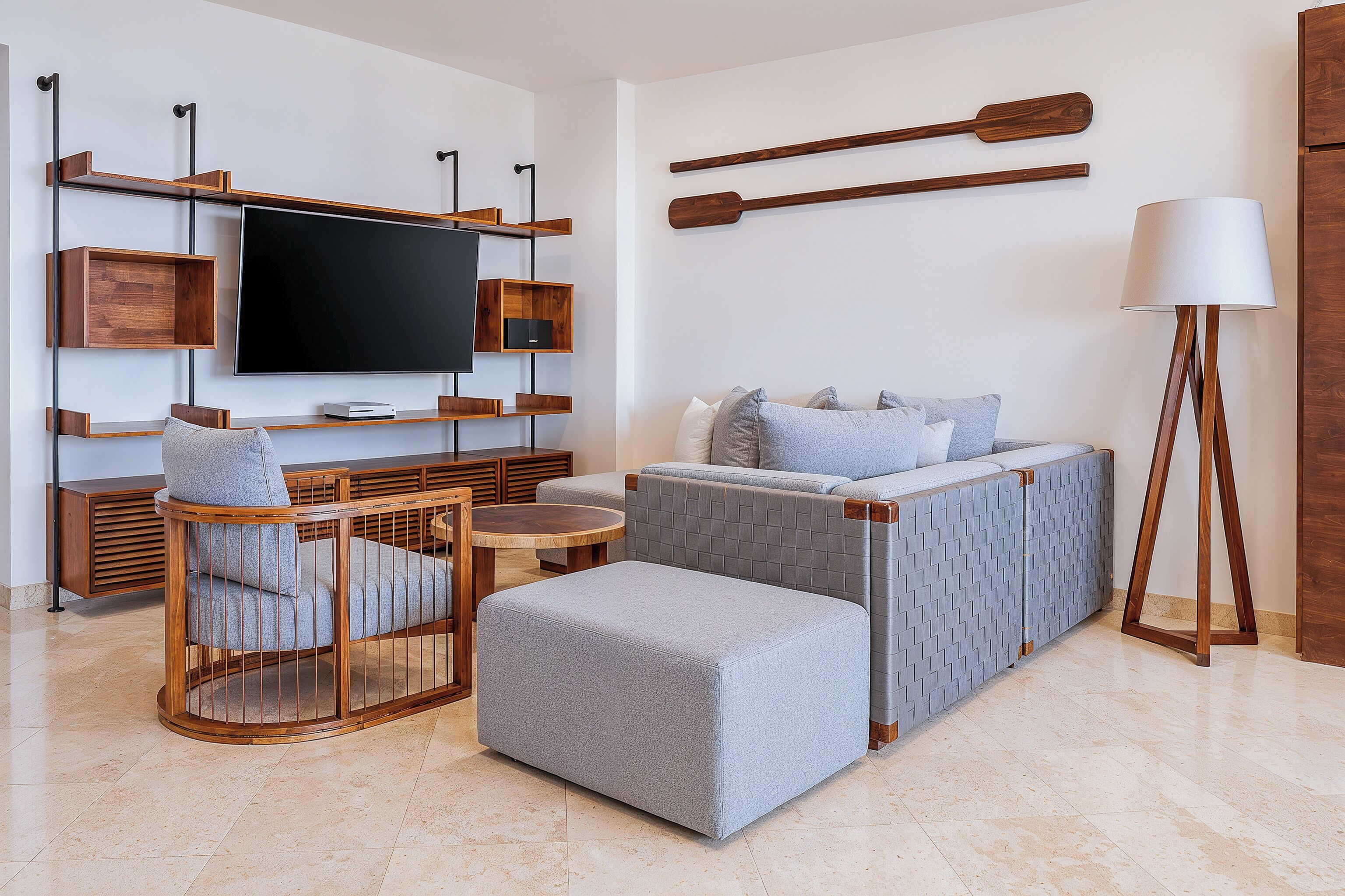 Un salon moderne avec un téléviseur à écran plat, des meubles en bois, un canapé et une lampe sur pied.