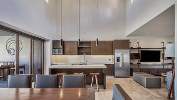 A modern kitchen with a central island, bar stools, and a dining area with a wooden table and chairs.