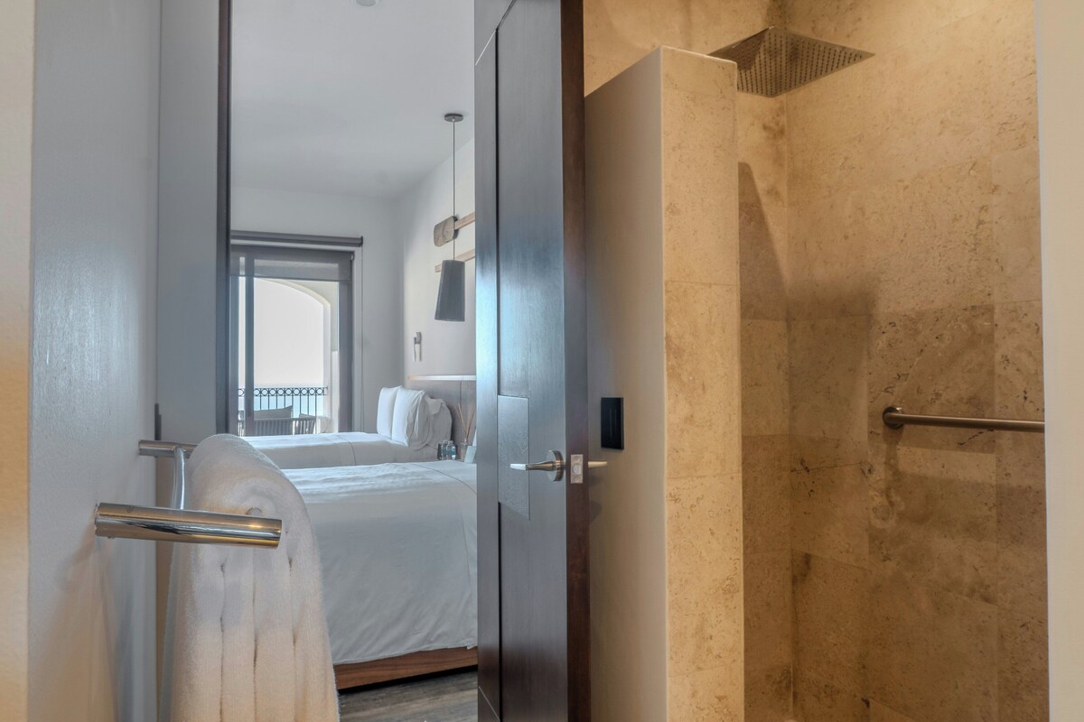 A hotel room with a bed, a shower, and a view of the outside.