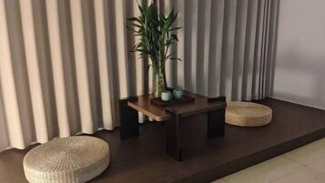 A modern room with a dark wooden table, a potted plant, and two woven poufs.