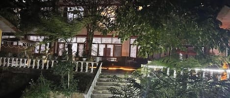 A nighttime view of a hotel with a water feature, a staircase, and a building with illuminated windows.