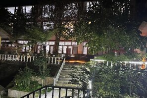 A nighttime view of a hotel with a water feature, a staircase, and a building with illuminated windows. - Sha.heyue. Hotel (Emeishan City)