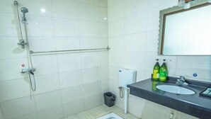Uma casa de banho com chuveiro, sanita, lavatório e garrafas de sabonete líquido.
