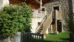 A stone building with a wooden staircase leading to a balcony. - Country Cottage / Gite - Usso, en Forez (Usson-En-Forez)